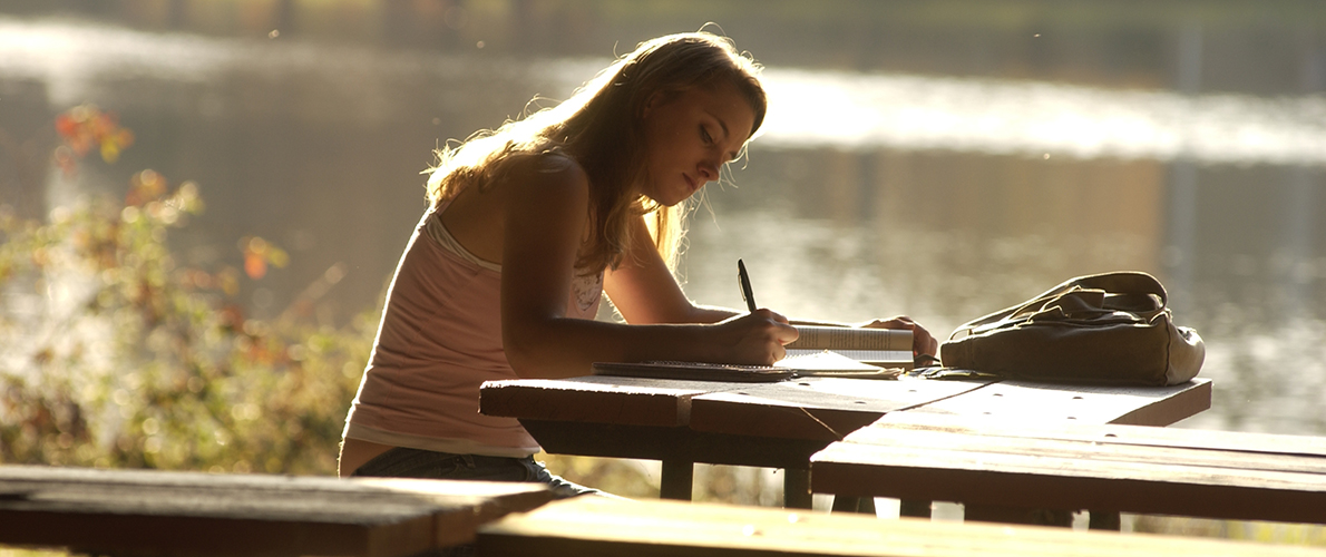 female student writing at bench